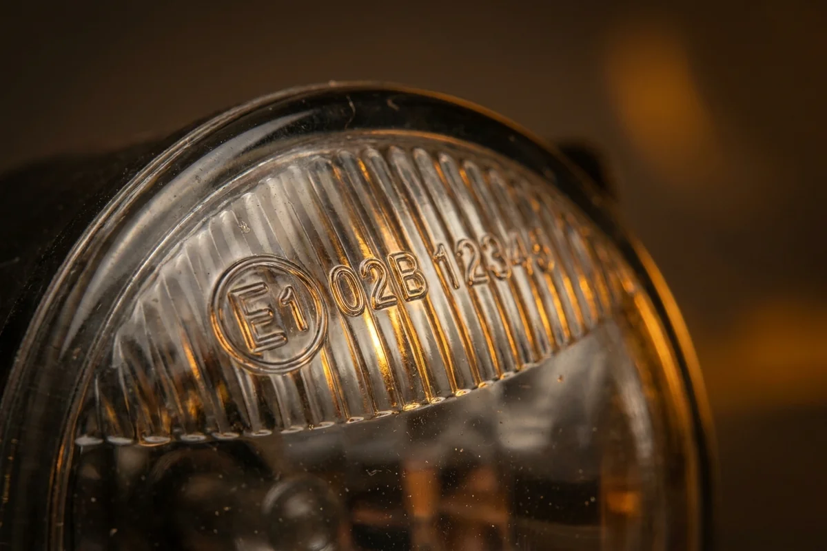 Oznaczenie homologacyjne E1 i symbol funkcji na kloszu przedniej lampy przeciwmgielnej