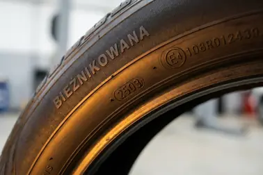 Bok opony bieżnikowanej z napisem RETREAD, znakiem E4 108R012439 i kodem daty bieżnikowania
