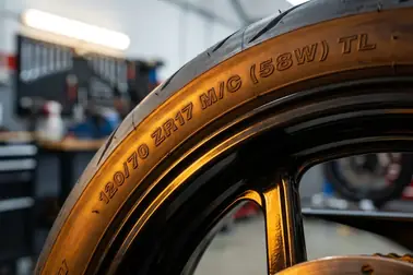 Bok opony motocyklowej z zaznaczonym zapisem 120/70 ZR17 M/C (58W) TL i kolejnością odczytu jego elementów