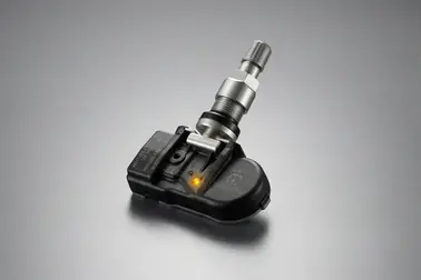Czarne, niewielkie pudełko elektronicznego czujnika ciśnienia wyposażone w połączony z nim metalowy zawór