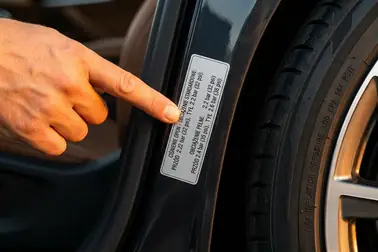 Kierowca porównujący oznaczenie XL na oponie z tabliczką zalecanego ciśnienia w samochodzie