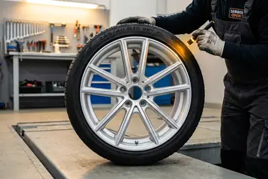 Mechanik sprawdzający uszkodzenia rantu felgi na poziomym stanowisku przed badaniem zbieżności