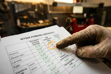 Mechanik wskazujący palcem wartość poza zakresem tolerancji na wydruku geometrii kół