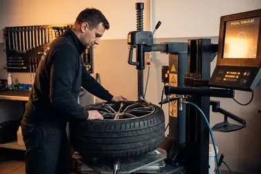 Mechanik wulkanizator montujący oponę Run Flat przy użyciu maszyny z dodatkowym ramieniem pomocniczym.