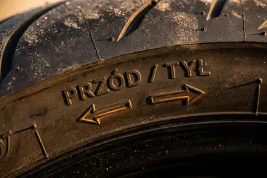 Oznaczenia FRONT, REAR oraz strzałki ROTATION na boku opony motocyklowej