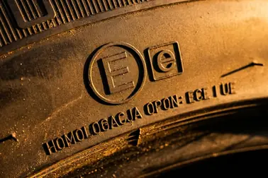 Porównanie dużej litery E w okręgu z małą literą e w prostokącie na boku opony