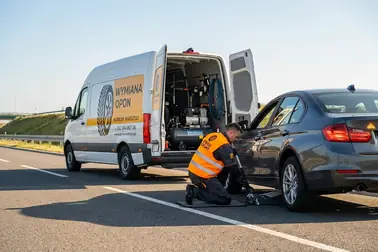 Samochód unieruchomiony w bezpiecznym miejscu oraz mobilny serwis przygotowujący stanowisko przy kole