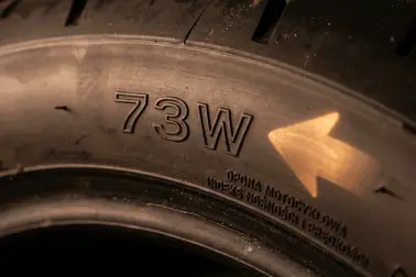 Zbliżenie na bok opony motocyklowej z widocznym indeksem nośności i prędkości 73W