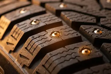 Zbliżenie na metalowe kolce trwale osadzone w bieżniku opony samochodowej