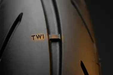 Znacznik TWI na boku opony motocyklowej i odpowiadający mu mostek w rowku bieżnika