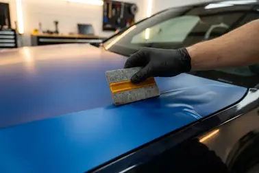 Aplikacja folii na panel samochodu z wypychaniem powietrza raklą od środka ku krawędzi