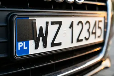 Czarna naklejka zasłaniająca niebieski pas i fragment urzędowego wzoru tablicy rejestracyjnej