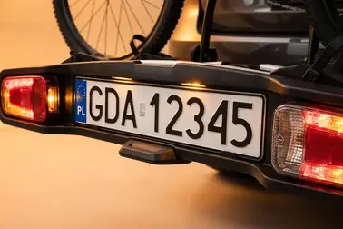 Dodatkowa tablica zamontowana w uchwycie platformy obok lamp pozycyjnych, STOP, kierunkowskazów i przeciwmgłowego