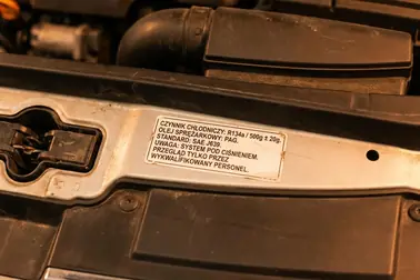 Etykieta układu klimatyzacji w komorze silnika z oznaczeniem rodzaju czynnika