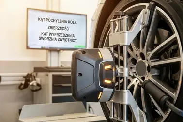 Głowica pomiarowa urządzenia do geometrii 3D założona na przednim kole samochodu
