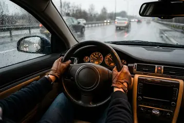 Kierowca trzymający oburącz kierownicę podczas przejazdu przez mokry odcinek drogi