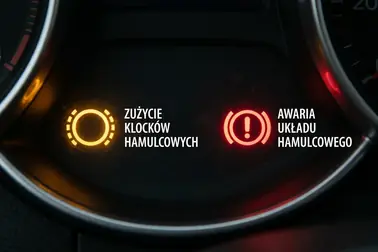 Kontrolka zużycia okładzin hamulcowych obok czerwonego symbolu układu hamulcowego