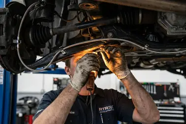 Mechanik dopasowujący i mocujący przewód hamulcowy pod samochodem