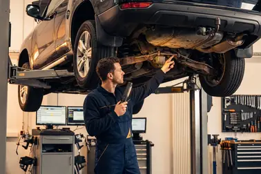 Mechanik kontrolujący przewody i zacisk podczas diagnostyki wycieku płynu hamulcowego