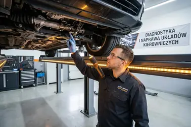 Mechanik sprawdzający na podnośniku źródło wycieku przy przekładni kierowniczej