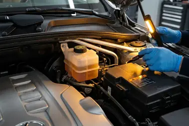 Mechanik sprawdzający poziom płynu w zbiorniczku wyrównawczym pod maską samochodu