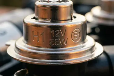 Oznaczenia H1, 12 V, 55 W oraz znak homologacji E na bańce i trzonku żarówki