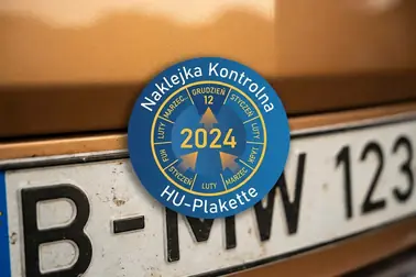 Plakietka HU na tylnej niemieckiej tablicy z zaznaczonym rokiem i miesiącem badania
