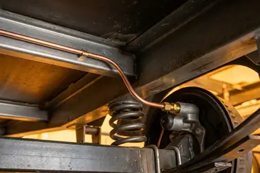 Przebieg sztywnego hydraulicznego przewodu hamulcowego poprowadzonego po ramie i osi przyczepy