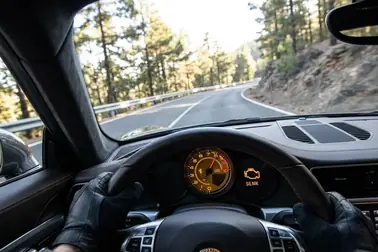 Samochód przyspieszający pod wzniesienie z migającą kontrolką check engine na zestawie wskaźników