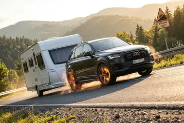 Samochód z przyczepą zjeżdżający górską drogą i intensywnie używający hamulców