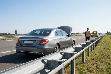 Unieruchomiony samochód stoi w bezpiecznym miejscu, a kierowca oczekuje na pomoc drogową z dala od ruchu.