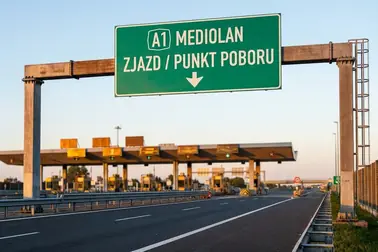 Zielony znak drogowy nad włoską autostradą wskazujący wjazd i stację poboru opłat