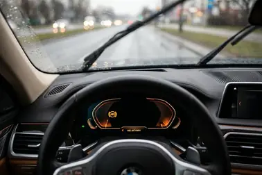 Żółta kontrolka ABS świecąca na desce rozdzielczej samochodu podczas jazdy w deszczu
