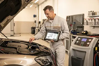 Mechanik sprawdzający instrukcję przed kontrolowanym płukaniem układu chłodzenia w warsztacie