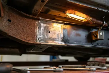 Oczyszczony fragment podwozia z usuniętym nalotem rdzy i widocznym stabilnym metalem