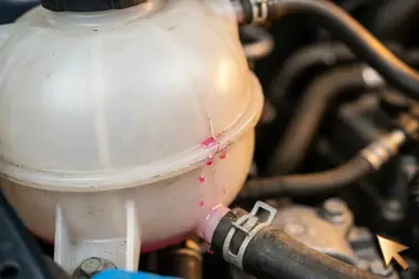 Pęknięcie na zgrzewie plastikowego zbiorniczka wyrównawczego z widocznym wyciekiem różowego płynu