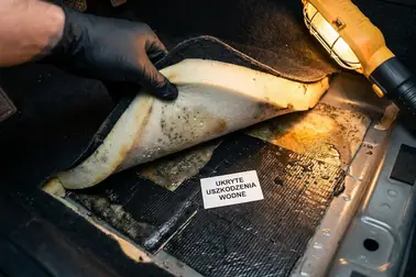 Uniesiona wykładzina samochodu odsłaniająca mokrą piankę i warstwę wygłuszającą