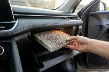 Wyciąganie zużytego filtra kabinowego zza schowka w samochodzie