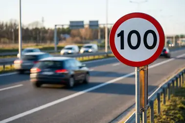 Znak B-33 z limitem 100 km/h ustawiony przy pasie autostrady